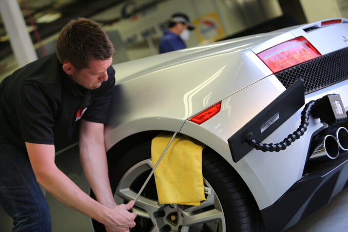 Successful PDR repairs. A worker performing paintless dent repair on a car.